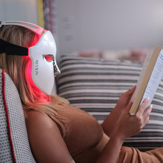 Woman relaxing with the Revilin Collagen Booster Mask 2.0 on red light